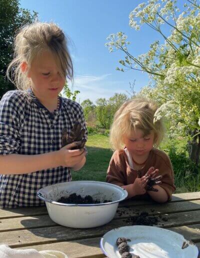 kinderen in mooie wilde tuin maken zaadbommetjes voor weelderige en bloemrijke bloemenweides