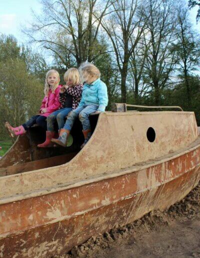 3 kinderen spelen op een boot in Woeste Willem aangelegd door hoveniers